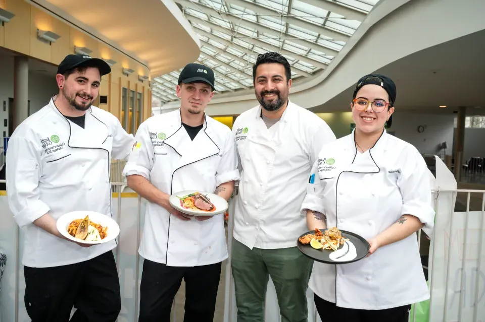 Four Smith chefs hold plates of food.